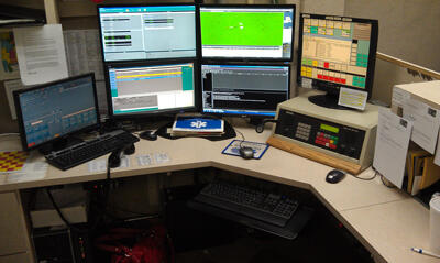 A desk with multiple monitors displaying various software.