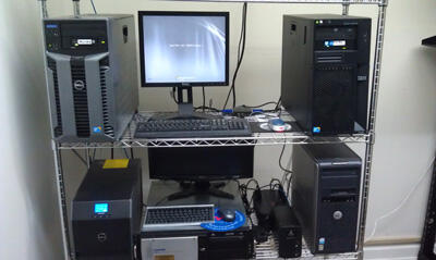 Several Computers on a tiered shelf.